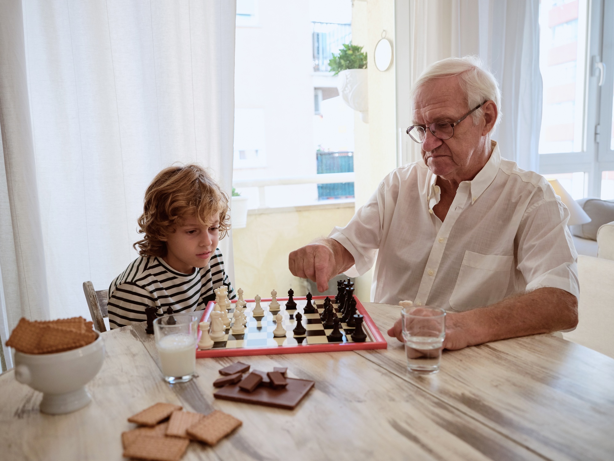 Grandfather and grandson playing board game at home